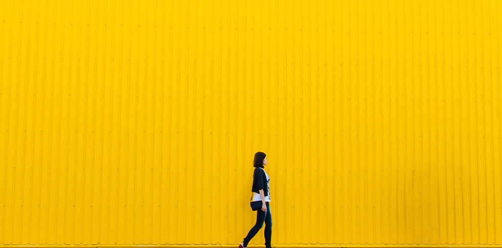 Woman walking in front of yellow wall